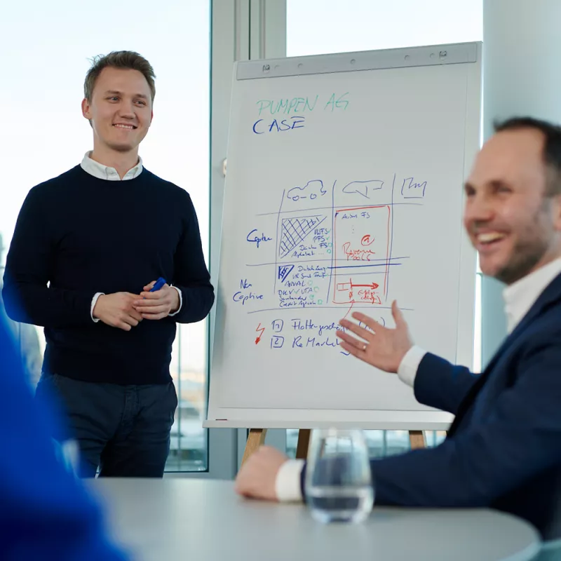 Ein junger Mann präsentiert an einem Flipchart die Lösung einer Aufgabe