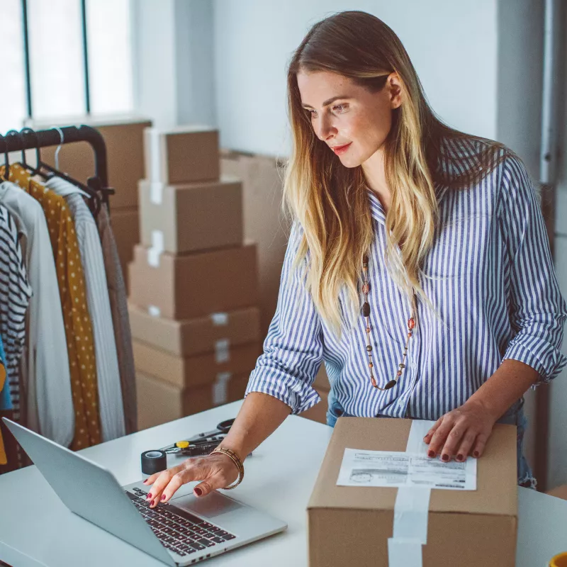 A woman in a boutique checks the address of a delivery on her laptop