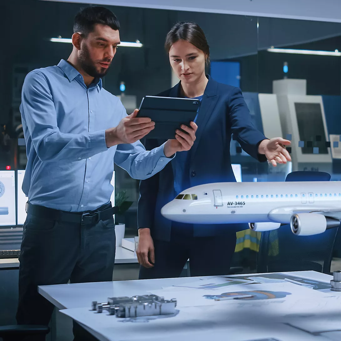 Eine Frau und ein Mann kontrollieren mit einem Laptop das Model eines Flugzeugs