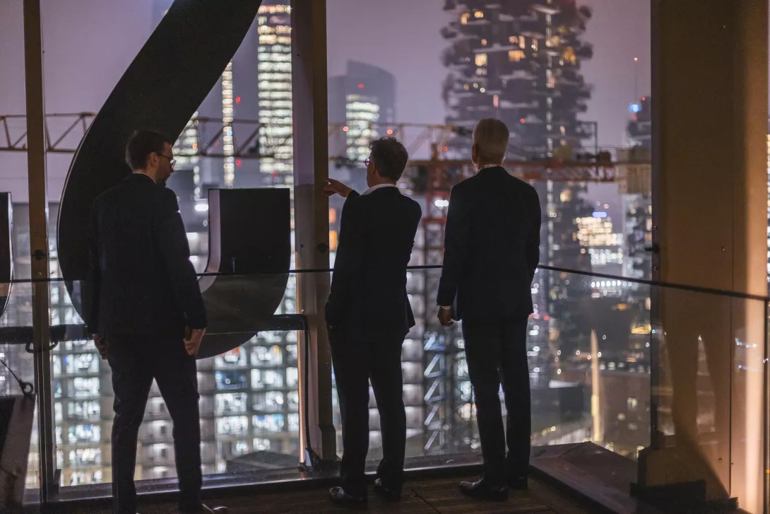 men standing on the rooftop pointing towards the city