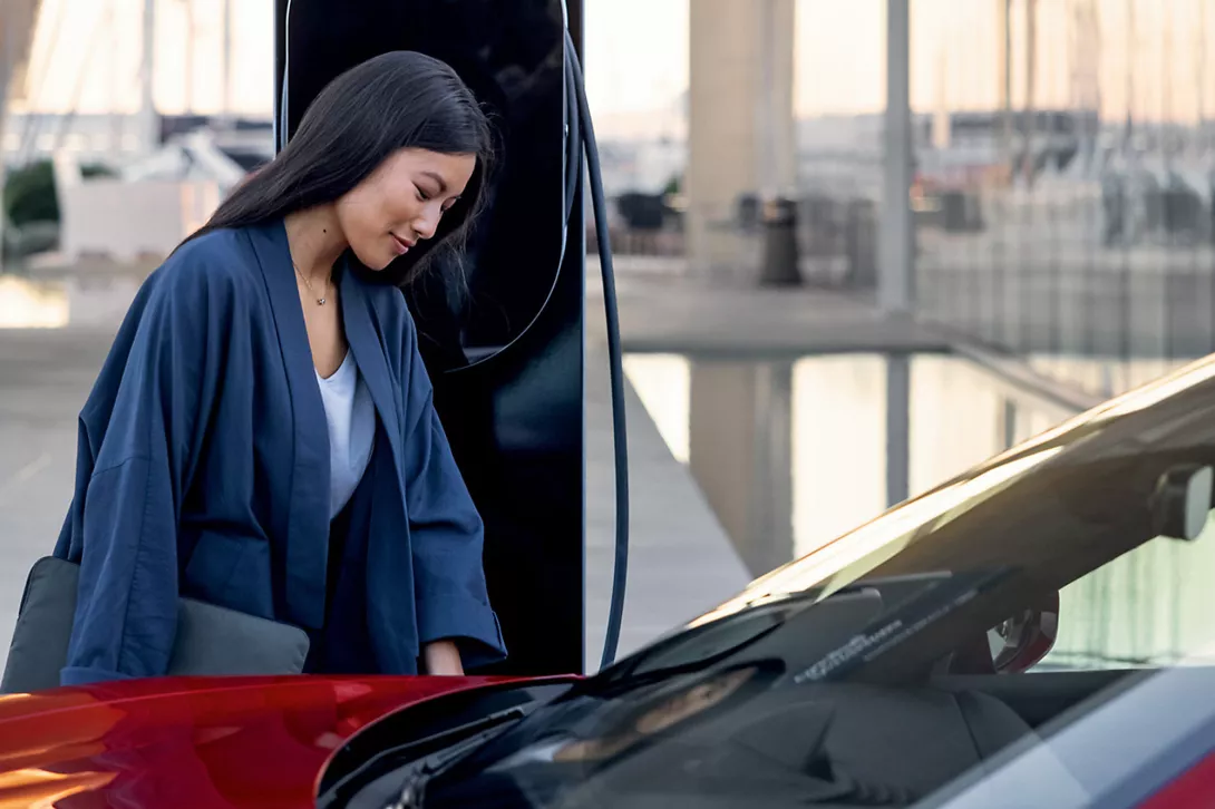 Woman in front of Porsche Charging the car at porsche electric power station