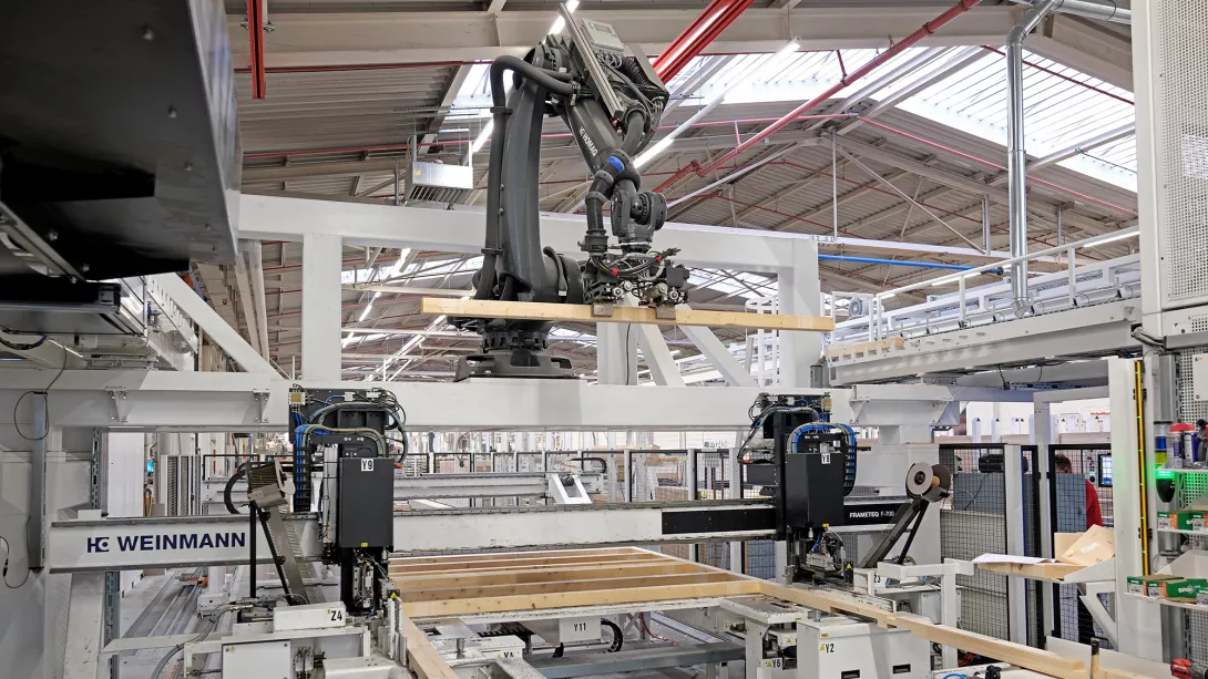 Präzision mit smarter Robotik: In der Riegelwerkstation im Werk Rheinau-Linx kommt die Anlagentechnik „smartPrefab“ des Maschinenbauers Weinmann zum Einsatz. Das Herzstück bildet ein Roboter. Er legt die Holzstiele aus drei verschiedenen Lagern vollautomatisch in das sogenannte Riegelwerk ein. 